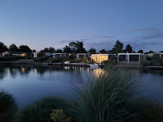 Veluwemeer 2022: Beleuchtete Ferienhäuser spiegeln sich in der Abenddämmerung im Wasser