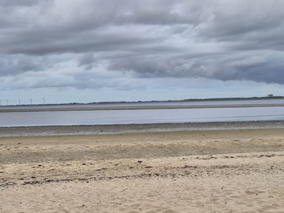 Yerseke 2026: Sandstrand bei Ebbe, Wolkenband über dem Wasser und Windräder am Horizont